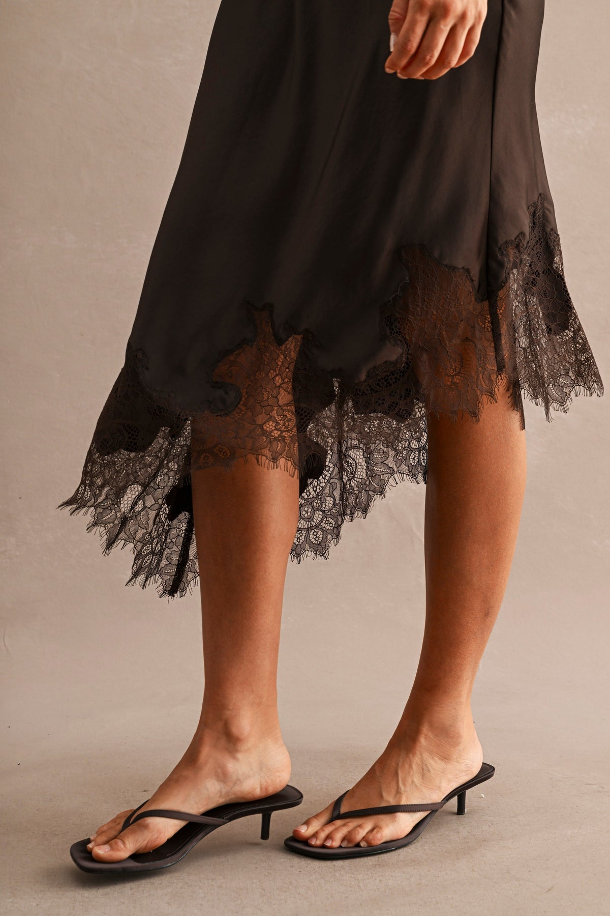 Women’s satin midi skirt with high waist, asymmetric hem and lace trim detailing.